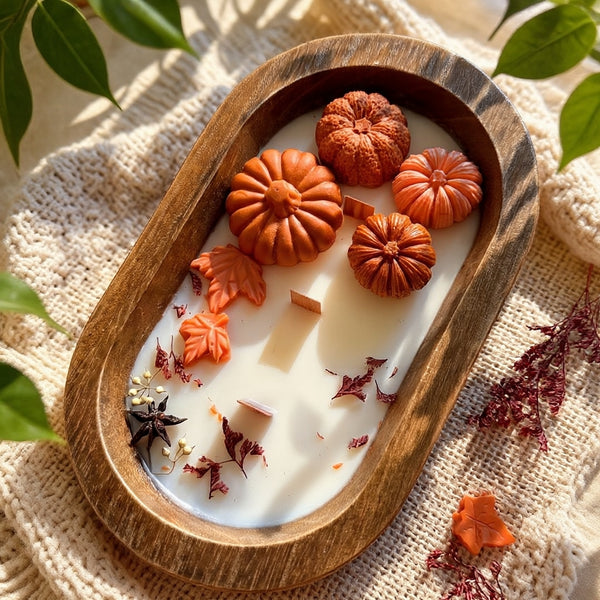 Pumpkin dough bowl candle on a chunky knit blanket beside a houseplant